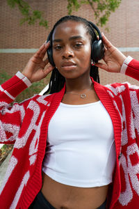 Portrait of young woman standing against wall