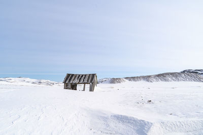 Lifeguard hut on snow covered land against sky