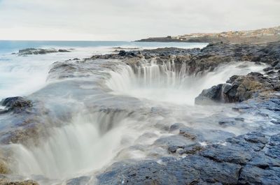 Scenic view of waterfall against sky