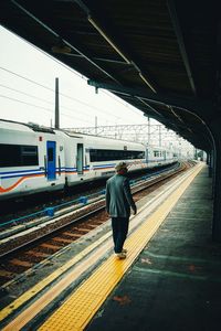 Rear view of man walking at railroad station platform