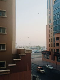 Cars on road by buildings against clear sky