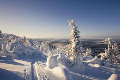 Snow covered landscape against clear sky