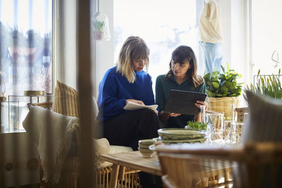 Female owners discussing over digital tablet at boutique