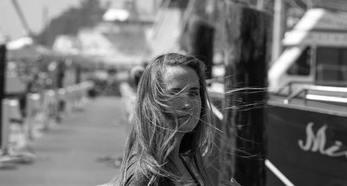 Portrait of woman with long hair on pier at harbor