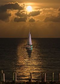 Sailboat on sea against sky during sunset
