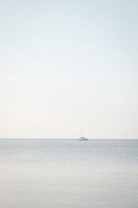 Sailboat sailing in sea against clear sky