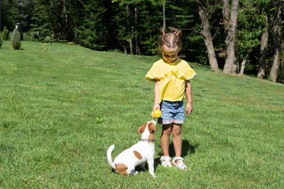 Portrait of boy playing with dog on field