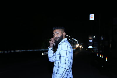 Man standing against illuminated city at night