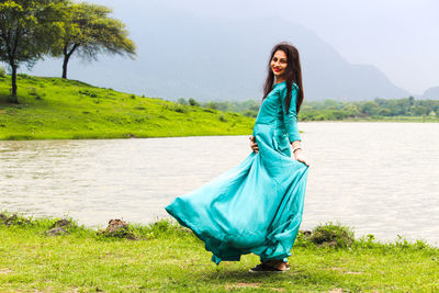 Full length of woman standing on grass at shore