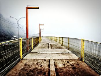 Railing by sea against clear sky