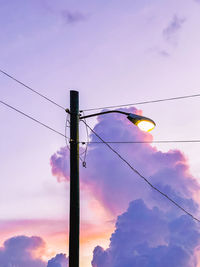 Low angle view of electricity pylon against sky during sunset