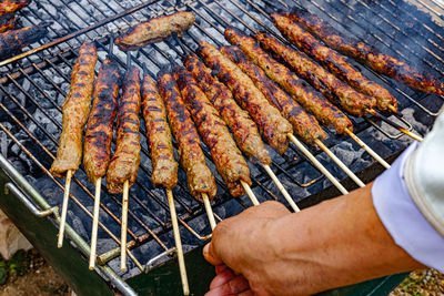 Cropped hand of man preparing kofta meat on barbecue grill