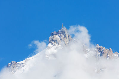 Low angle view of snowcapped mountain against blue sky