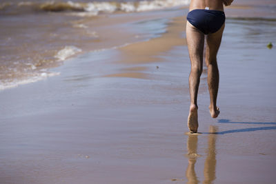 Low section of man in underwear running at beach