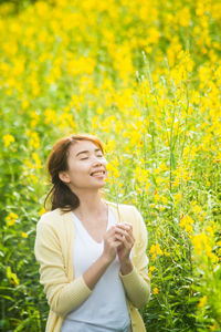 Smiling woman smelling yellow flowering plants