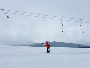 Man skiing on snow covered mountain against sky