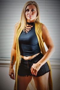 Portrait of beautiful young woman standing against wall