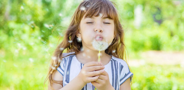 Cute girl blowing dandelion seed