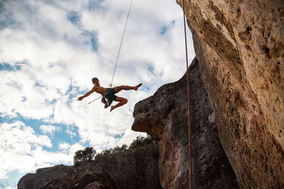 Low angle view of person on rock against sky