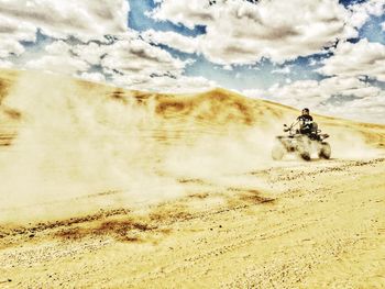Man riding motorcycle in desert against sky