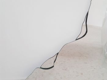 Close-up of broken mirror against white wall