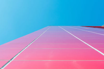 Low angle view of road leading towards building against clear blue sky