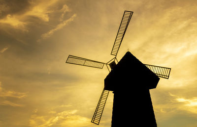 Low angle view of traditional windmill against sky during sunset