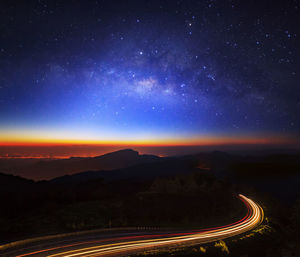 Aerial view of light trails on road against sky at night