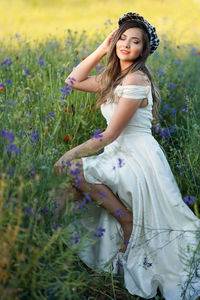 Portrait of young woman standing amidst plants on field
