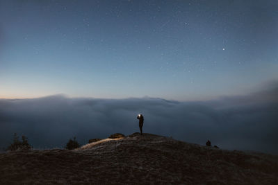 Rear view of man standing on mountain against sky