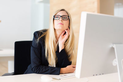 Portrait of young woman using phone while sitting on table