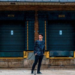 Full length portrait of man standing against wall