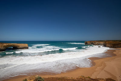 Scenic view of beach against clear blue sky