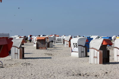 Hooded chairs on beach against clear sky