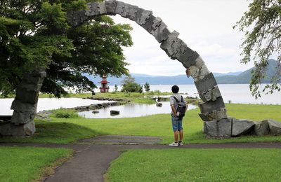 Rear view of man standing on footpath by trees