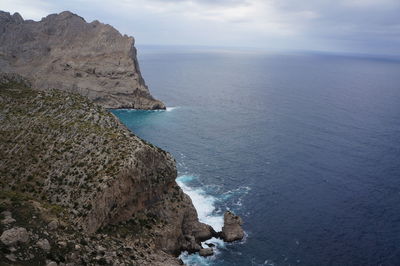 View of calm sea against rocky mountain