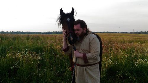 Young woman with horse standing on field