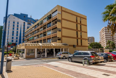 Cars parked on street by buildings in city against sky