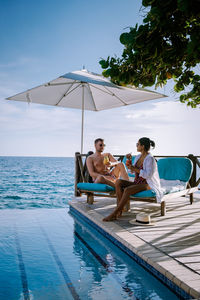 Young couple sitting on swimming pool