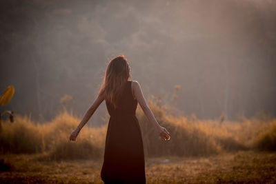 Rear view of woman with long hair standing on field