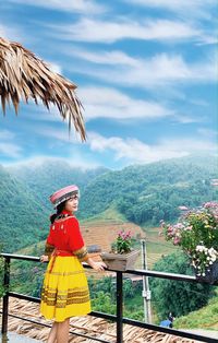 Woman sitting at park against sky