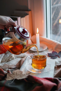 Cropped hand holding lit candle on table