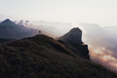 Silhouette man jumping over mountain against sky