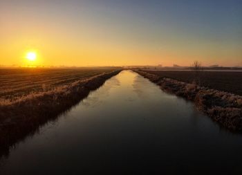 Scenic view of agricultural field against sky during sunset