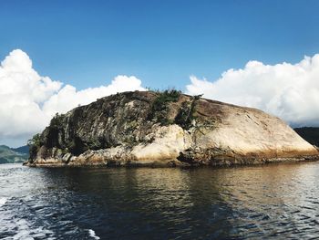 Rock formations by sea against blue sky