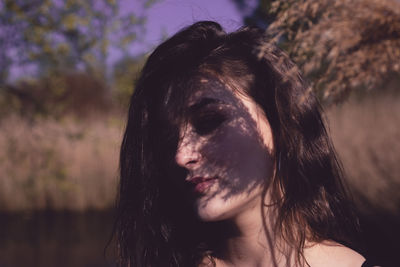 Close-up of woman with shadow on face against plants