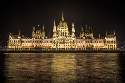 Illuminated hungarian parliament building by danube river at night