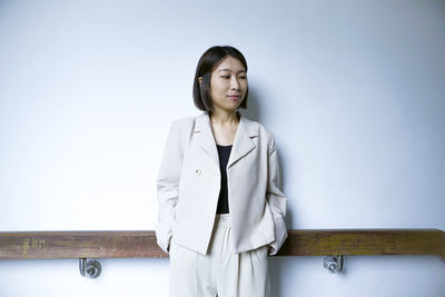 Portrait of young woman standing against wall