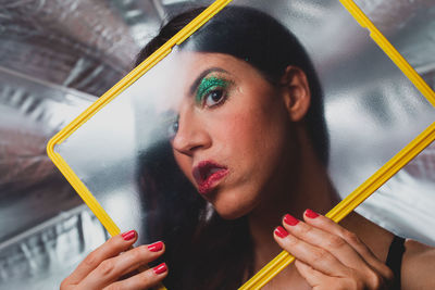 Close-up portrait of woman with make-up seen through glass