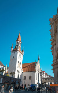 Low angle view of old town hall against clear blue sky